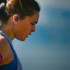 woman wearing smartphone armband and blue earphones